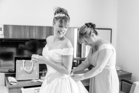 Wedding Photography in Buckinghamshire. Bride with bridesmaid helping with the dress.