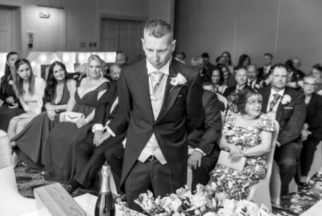 Wedding Photography in Buckinghamshire. Groom in thought with family behind him before the ceremony.
