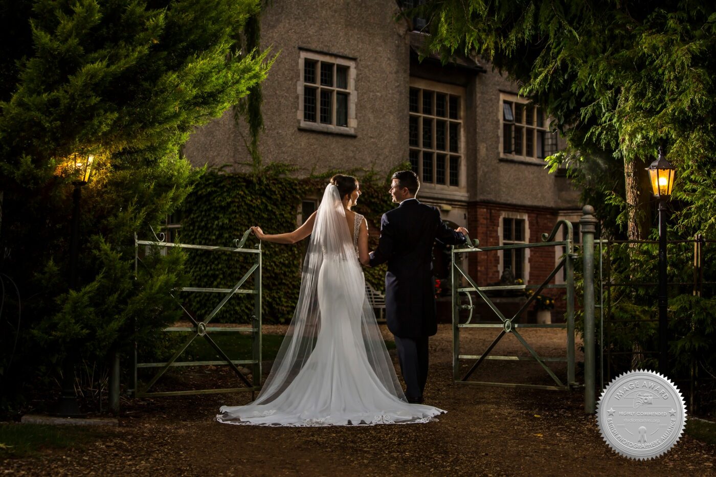 Award Recognition for Midlands Wedding Photographer - The award-winning image taken at Plum Park Manor. An evening shot of the newlyweds at the entrance gate to the venue.
