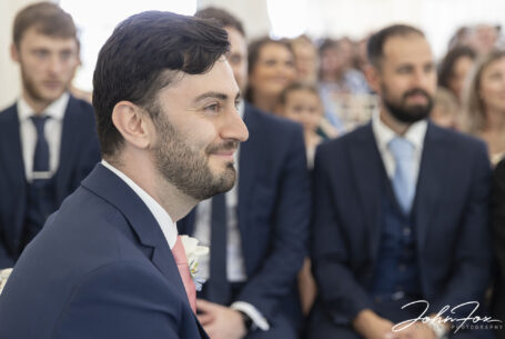 Groom with guests in the background in ceremony at a Warwickshire Wedding.