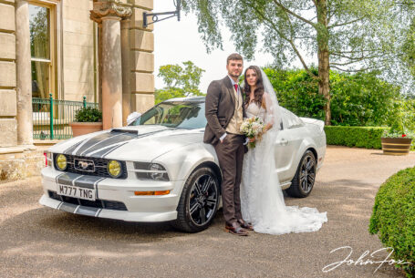 Bride and groom with wedding car outside the Leicestershire wedding venue.