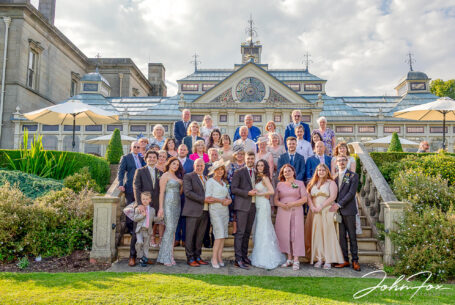 Group image of all wedding guests with bride and groom on the steps at Kilworth House.