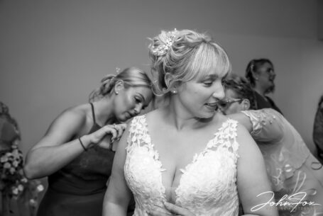 Bridal preparations. The bridesmaids helping out. Image by John Fox Wedding Photography.