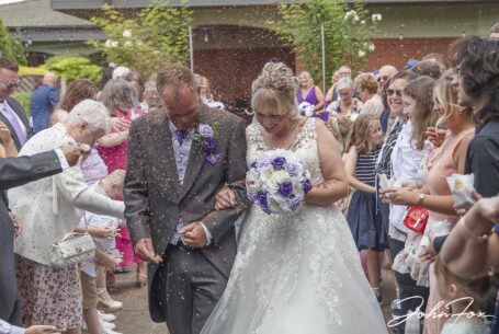Bride and groom with guests throwing confetti.