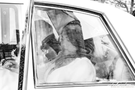 Bride arriving at church photograph taken looking through a misted car window by John Fox Wedding Photography