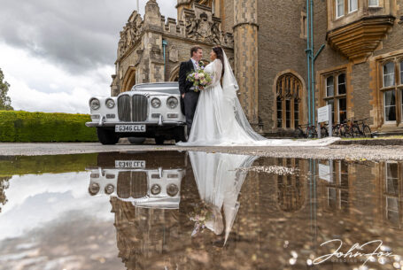 Bride and groom and wedding car reflection in a puddle at Tortworth Court in Gloucestershire.