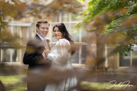 Bride and groom photographed though trees in the grounds at Tortworth Court in Gloucestershire