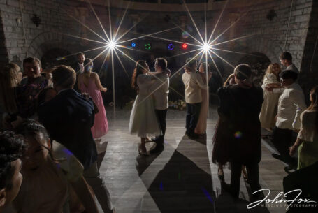 Bride and groom with guests dancing around them.