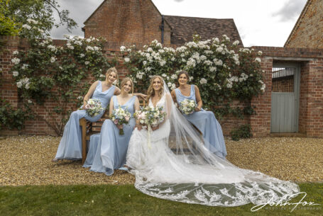 Bride and bridesmaids sitting on a garden bench at Primrose Hill Farm