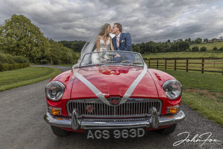 Bride and groom kissing in the car. Oxfordshire wedding photography by John Fox.