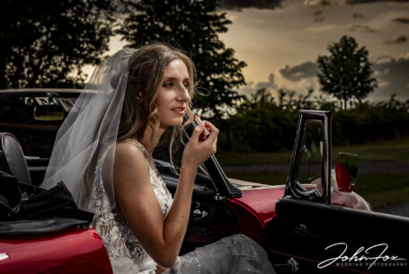 Wedding photographer in Oxfordshire at Primrose Hill Farm. Bride putting on lipstick in the car.