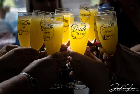 Bucks fizz glasses together with bride's glass hitting the light