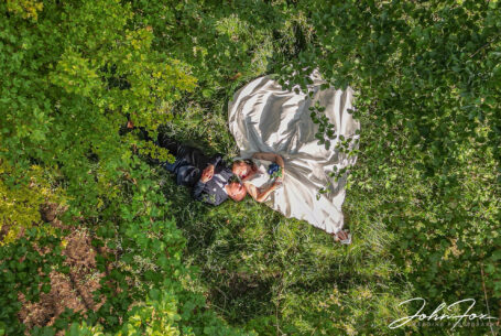 Bride and groom laying in woodland. Image taken using a drone.