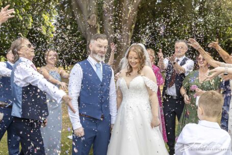 Confetti image as guests throw confetti over bride and groom at their Warwickshire wedding. Image by John Fox Wedding Photography.