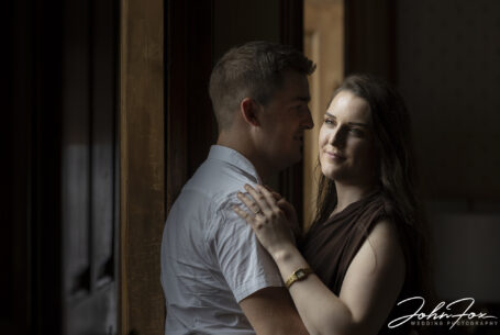 Pre-wedding shoot showing bride and groom by a window. Image uses natural light to promote the bride.