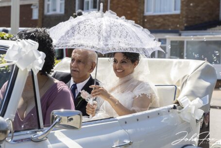 Bride and dad arriving at St Martin de Porres Church in Bedfordshire in an open top car
