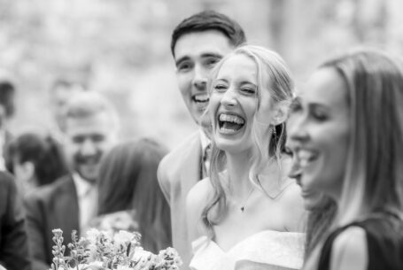 Bride and Groom laughing with their guests - Image by John Fox Wedding Photography at Ashley Wood Farm, Wiltshire.
