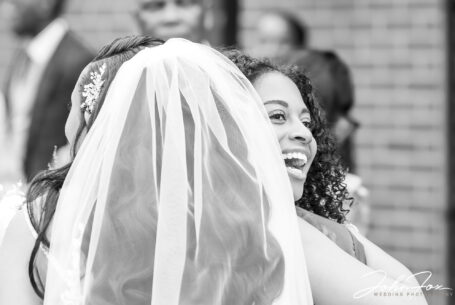 Bride and wedding guest hugging after the ceremony at the Kingdom of Jehovah’s Witnesses Church, Birmingham.