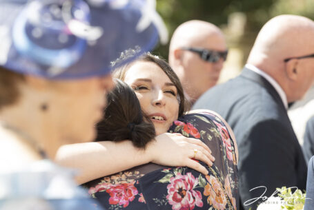 Wedding guests hugging the bride at Chicheley Hall in Buckinghamshire. John Fox Wedding Photography.