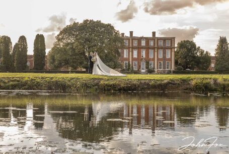 Bride and groom with Chicheley Hall in the background and reflection in a lake