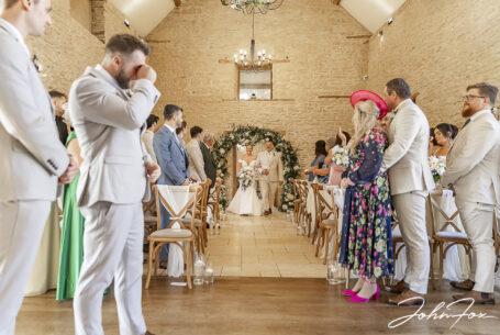 Here comes the bride as the groom can't help crying at their wedding at Kingscote Barn, Tetbury