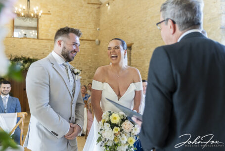 Bride and groom laughing during their wedding ceremony at Kingscote Barn in the Cotswolds