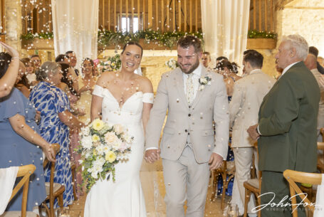 Bride and groom walking down the aisle and being showered with Confetti at their Tetbury wedding