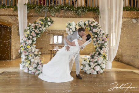 Dip kiss with confetti at Kingscote Barn, Tetbury. Photo by John Fox Wedding Photography