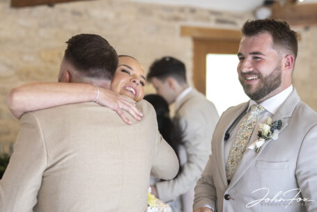 Bride being hugged by a guest at her Kingscote Barn wedding
