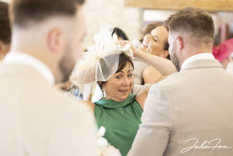 Groom's Mum readjusting her hat. Photo by John Fox Wedding Photography