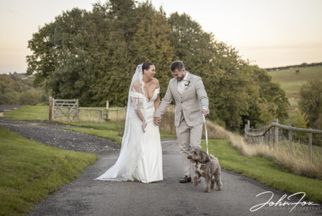 Bride and groom with their dog in the grounds at Kingscote Barn, Tetbury