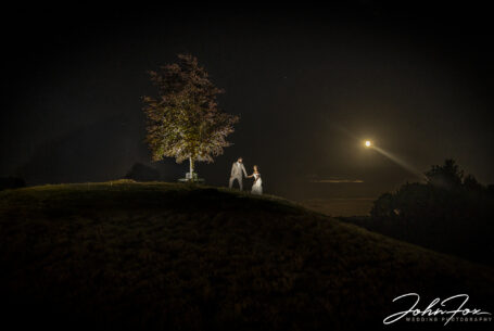 Bride and groom at night with the moonrise in the background at Kingscote Barn, Tetbury