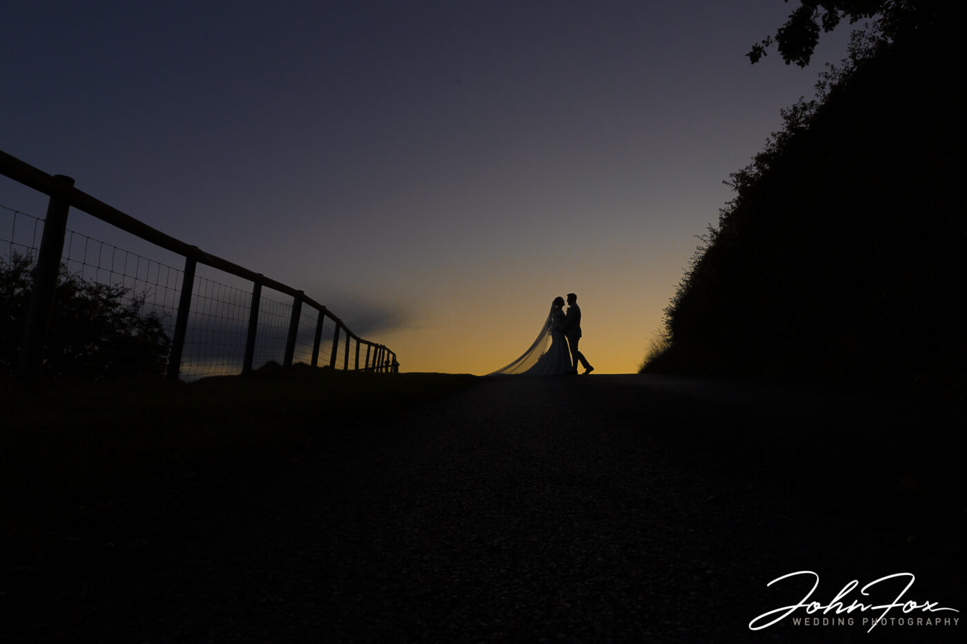 Gabrielle and William’s Wedding at Kingscote Barn, Tetbury. Image of the happy couple silhouetted against the evening sky.