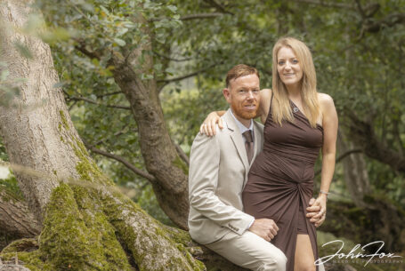 Pre-wedding shoot showing the couple sat in woodland at the Fawsley Estate in Northamptonshire. Image by John Fox Wedding Photography.