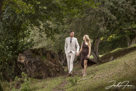 Pre-wedding shoot image by John Fox of Tanya and Shane walking through woodland at the Fawsley Estate in Northamptonshire.