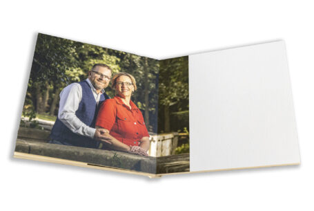 Joanne and Kevin's Wedding guest book featuring images from a pre-wedding shoot at Rushton Hall. The happy couple standing by a wall in the grounds of the Hall.