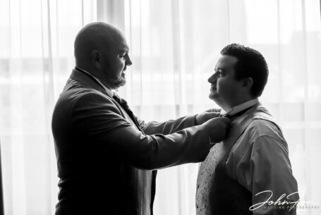Groom being helped with his bow tie by the best man. Image by John Fox Wedding Photography.