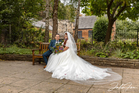 Amy and Karl sitting on a bench in the Trinity House Herb Garden in Leicester.