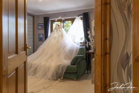Image of Sarah's dress hanging up in window. Staffordshire wedding photographer John Fox.