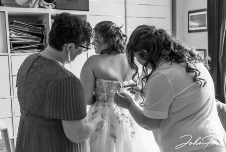 The bride, Sarah, getting into her wedding dress. Staffordshire wedding photography by John Fox.