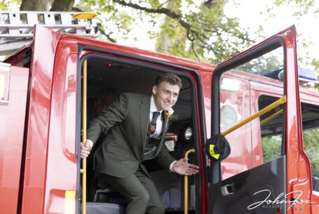 Lewis, the groom, arriving at the ceremony in a fire engine. Staffordshire Wedding Photography from John Fox.