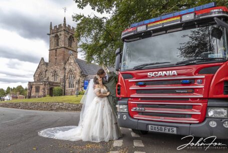 The newly-wedded couple kissing by the fire engine.