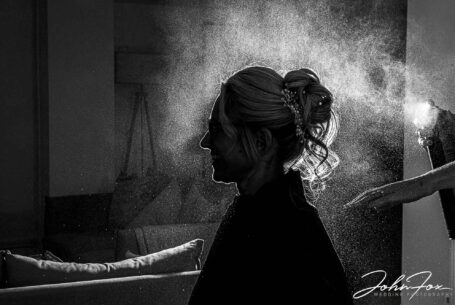 Bride silhouetted while hairspray is used in preparation for her Wedding in Bedfordshire. Photo by John Fox Wedding Photography