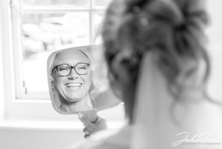 Lynn laughing while being reflected in a mirror. John Fox, Wedding photographer in Bedfordshire.