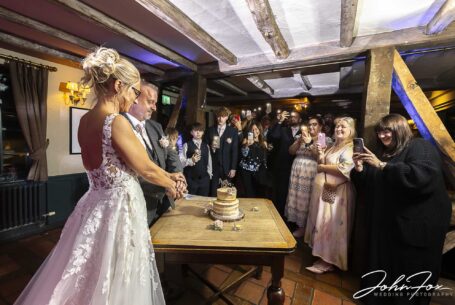Bride and groom cutting the cake with guests at The Five Bells pub wedding venue in Stanbridge