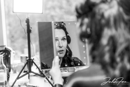 The bride, Amanda, checking her makeup in a mirror. Wedding Photography by John Fox.