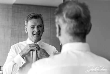 The groom in a mirror as he prepares for his Chelsea Registry Office Wedding. Image by John Fox Wedding Photography.