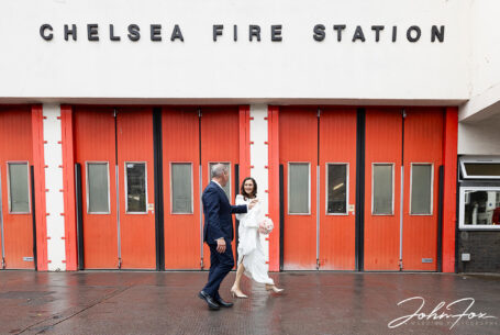Bride and groom walking past Chelsea Fire Station. Wedding Photography in London by John Fox.