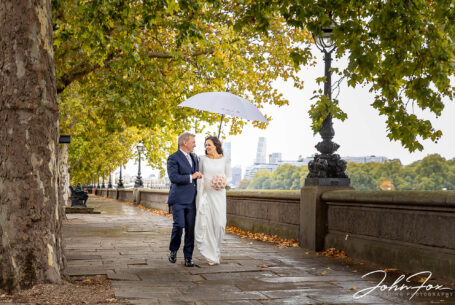 Bride and groom walking on the Thames embankment after their Chelsea Registry Office Wedding