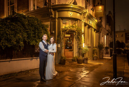 Bride and groom standing outside The Phene at night.